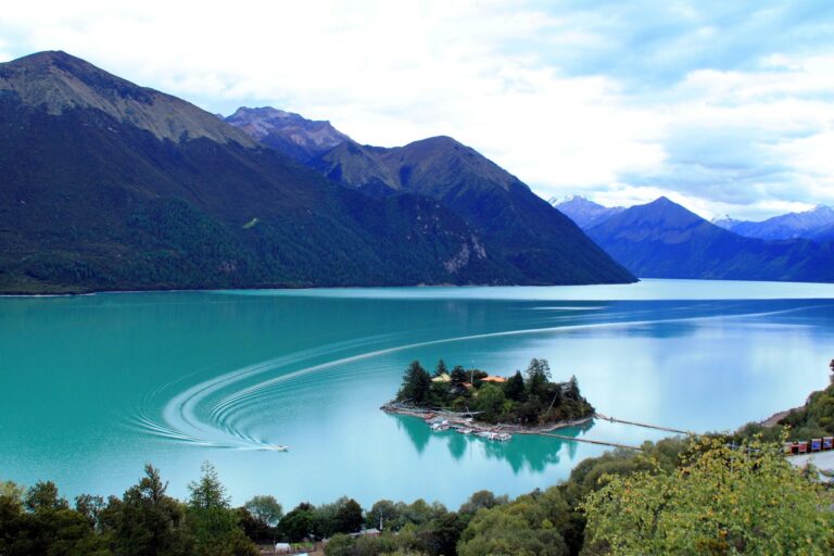 Tsozong island in turquoise Basum Tso lake below forested mountains
