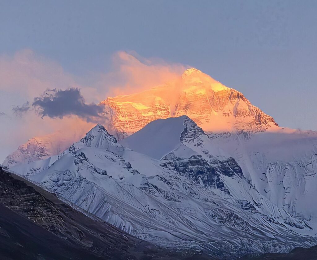 Everest summit lit at sunset above cloud