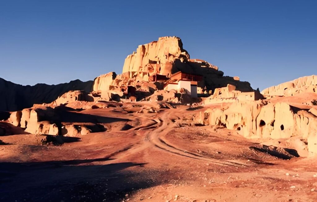 Guge Kingdom ruins above the dirt road in evening light