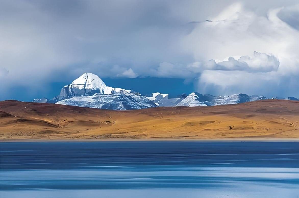 Mount Kailash across a lake under big clouds