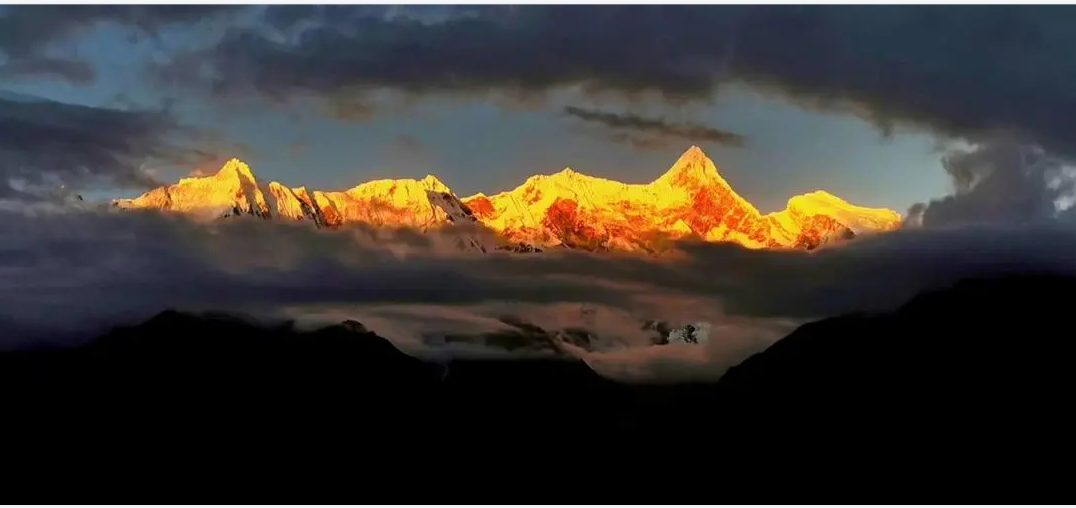 Namcha Barwa peak lit gold above dark cloud